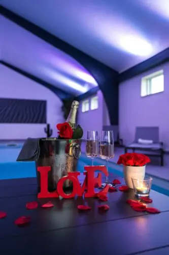 Image d'une bouteille de champagne et de décoration de saint valentin en face de la piscine intérieur